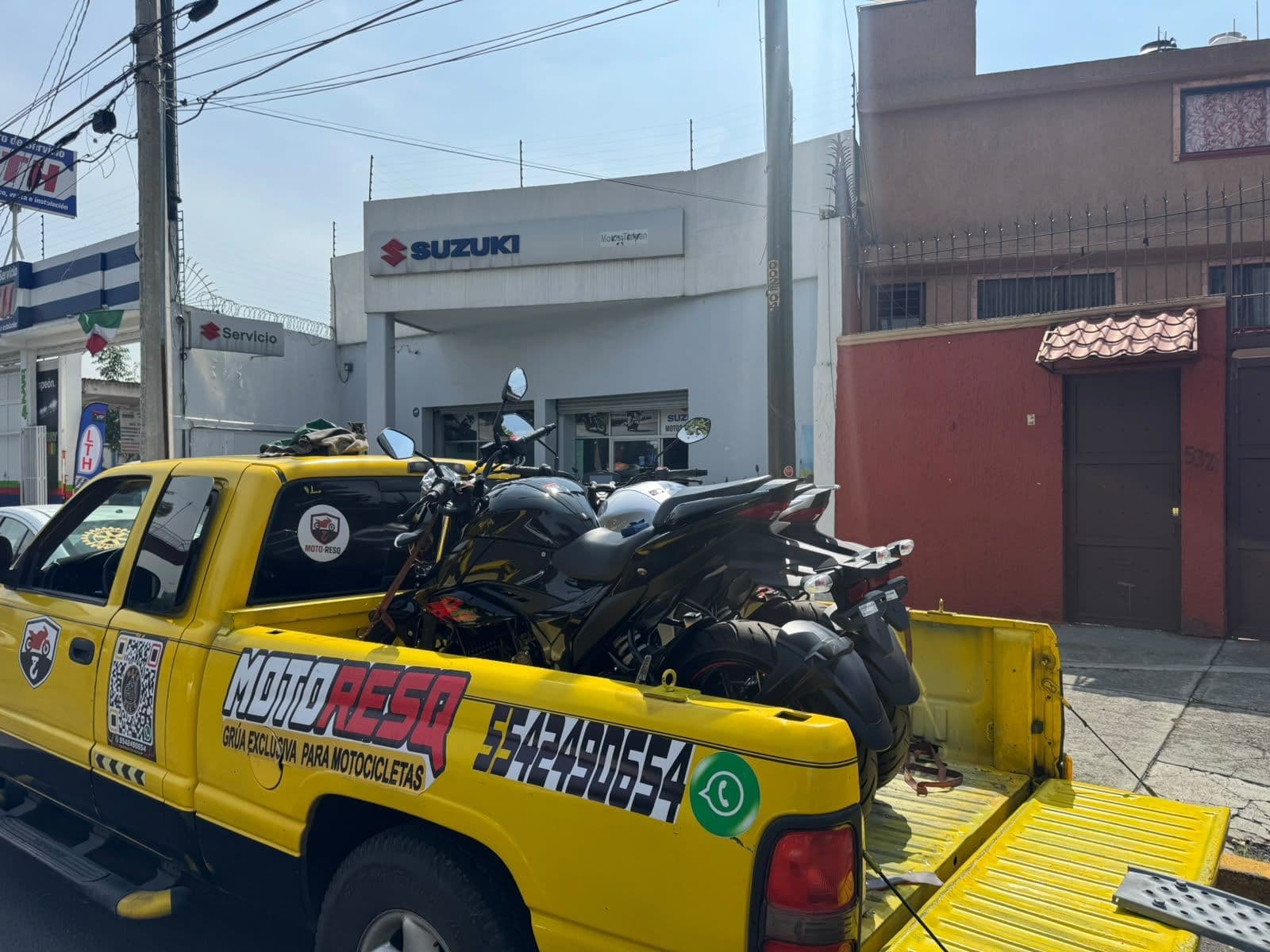 Grúa de Moto-ResQ con una motocicleta frente a una agencia Suzuki