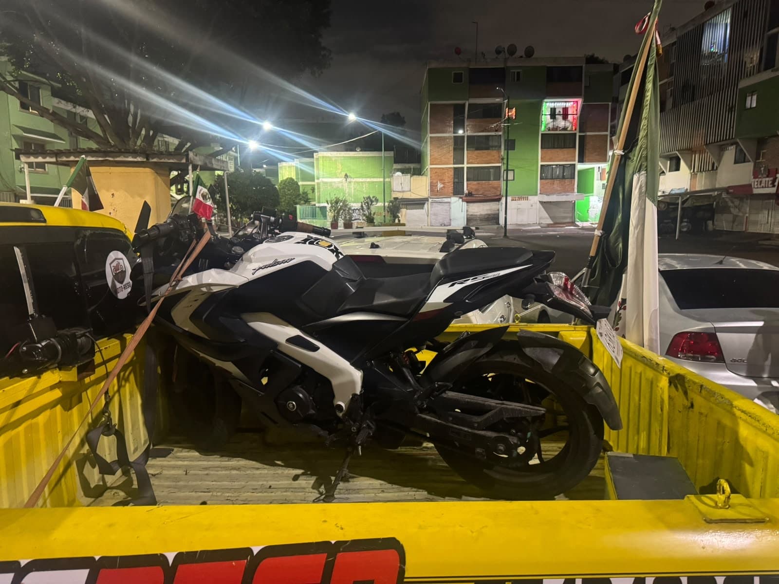 Motocicleta Bajaj Pulsar RS200 blanca asegurada en la grúa de Moto-ResQ, de noche